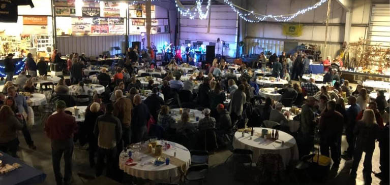 People eating dinner in barn with band playing in corner